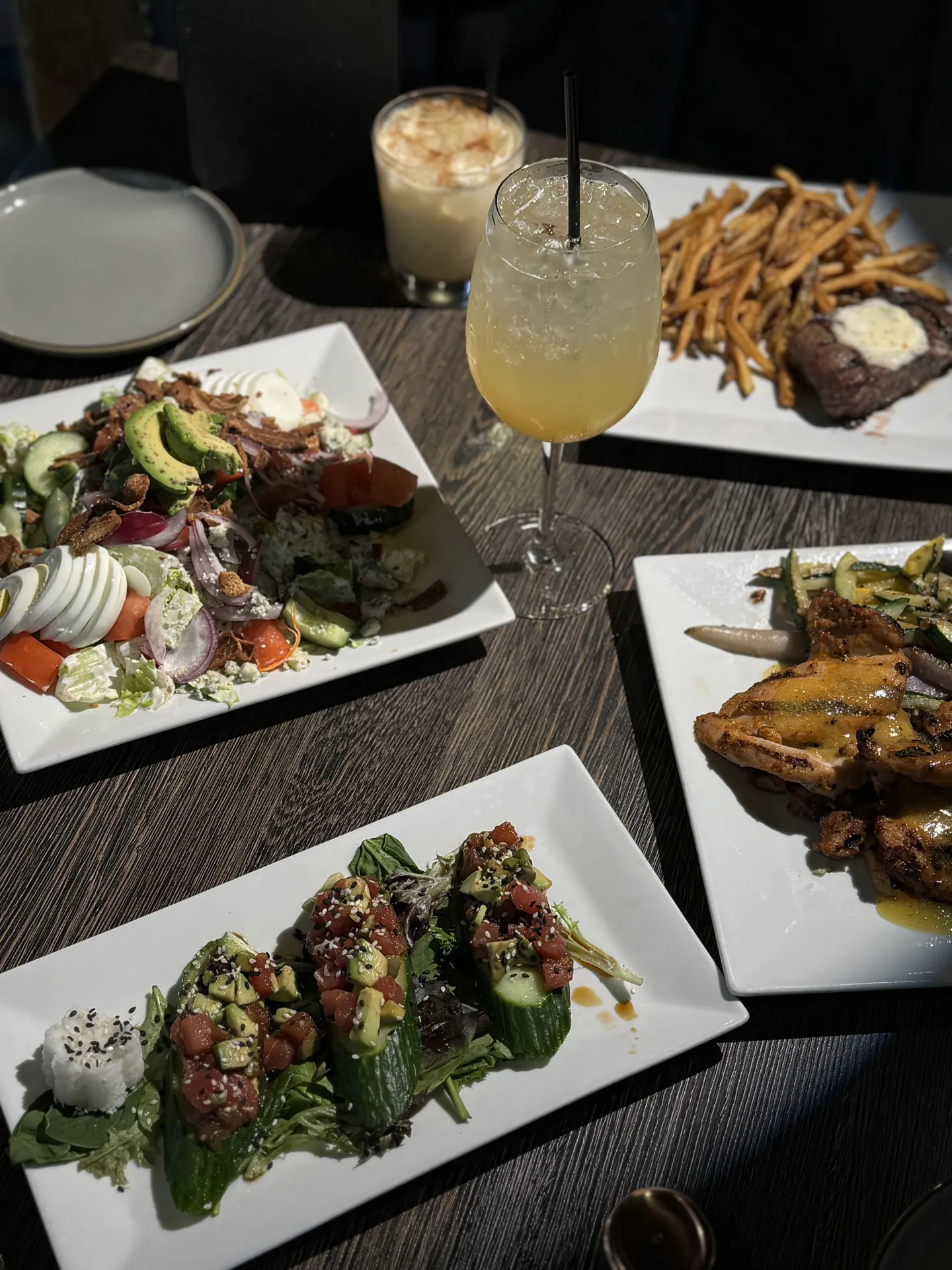 Table spread of Cobb salad, tuna bites, steak frites and cocktails at GreenHouse in New Hope, PA
