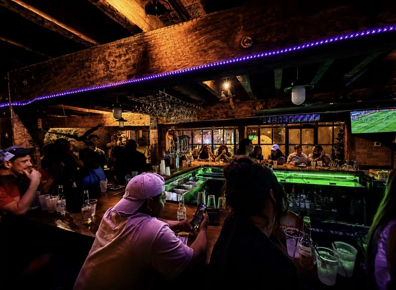 Busy indoor bar at night with neon lighting and exposed beams at GreenHouse in New Hope, PA